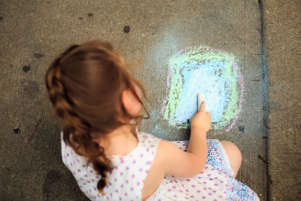 little-girl-drawing-on-pavement-with-colored-chalk-2414839